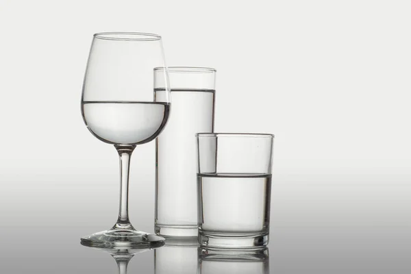 Tasse Und Gläser Mit Wasser Auf Weißem Hintergrund Und Oberfläche — Stockfoto