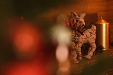 Kırmızı ve kahverengi gölgeli modern iç mekan, mum, buzağı oyuncağı ve şöminenin üzerinde duran diğer Noel süsleri.. 