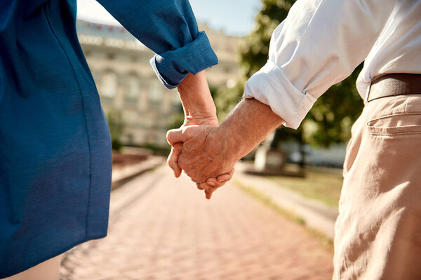 You and me forever. Close-up of elderly couple holding hands while walking together outdoors