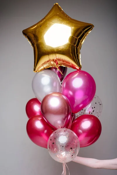 Beyaz, pembe, şeffaf helyum balonları ve altın yıldızdan oluşan bir kompozisyon..