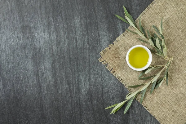Tabaktaki zeytinyağı manzarası, ahşap arka planda. Dalları olan zeytinyağı. Etrafında dallar olan beyaz tabakta doğal zeytin yağı. Metin veya ürün için alanı kopyala.
