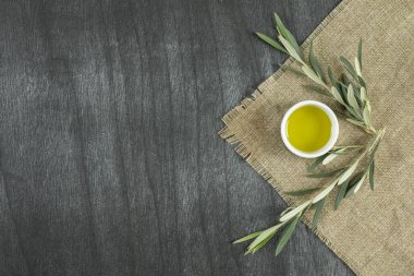 Tabaktaki zeytinyağı manzarası, ahşap arka planda. Dalları olan zeytinyağı. Etrafında dallar olan beyaz tabakta doğal zeytin yağı. Metin veya ürün için alanı kopyala.