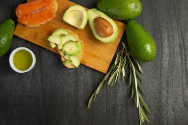 Avokado dilimli ekmek. Taze somon ve avokado sandviçi. Sağlıklı gıda konsepti. Zeytinyağı ve zeytin dalı. Metin için alanı kopyala.