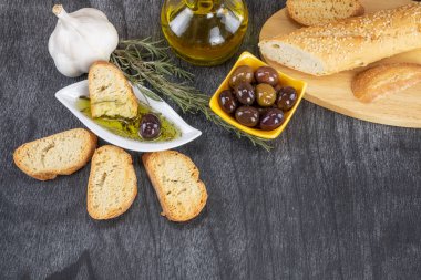 Zeytinyağına batırılmış zeytinyağlı ekmek. Yunan zeytinyağlı ekmek sosu. Beyaz kasede zeytinyağı sosu ve ahşap zemin üzerinde Yunan zeytinleri. Uzayı metin için kopyala. Ekmek batırma konsepti Akdeniz yemekleri.