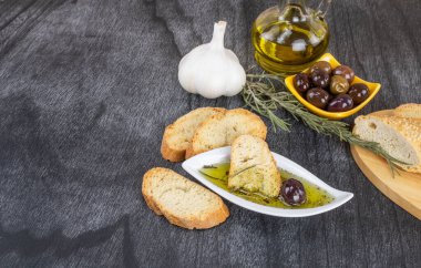 Zeytinyağına batırılmış zeytinyağlı ekmek. Yunan zeytinyağlı ekmek sosu. Beyaz kasede zeytinyağı sosu ve ahşap zemin üzerinde Yunan zeytinleri. Uzayı metin için kopyala. Ekmek batırma konsepti Akdeniz yemekleri.