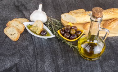 Zeytinyağına batırılmış zeytinyağlı ekmek. Yunan zeytinyağlı ekmek sosu. Beyaz kasede zeytinyağı sosu ve ahşap zemin üzerinde Yunan zeytinleri. Uzayı metin için kopyala. Ekmek batırma konsepti Akdeniz yemekleri.