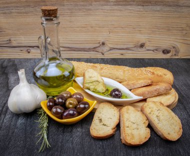 Zeytinyağına batırılmış zeytinyağlı ekmek. Yunan zeytinyağlı ekmek sosu. Beyaz kasede Yunan sosu ve ahşap arka planda Yunan zeytinleri. Zeytinyağı ve baharatlar. Ekmek batırma kavramı.