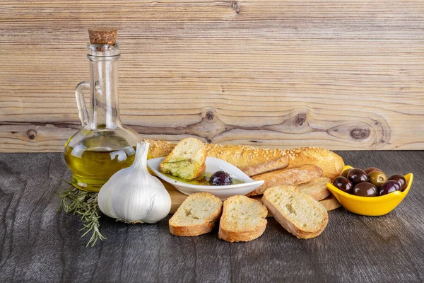 The bread dipped in olive oil with olive. Greek olive oil bread dip. Greek sauce in white bowl & Greek olives on wood background. Olive oil and spices. Bread dipping concept.
