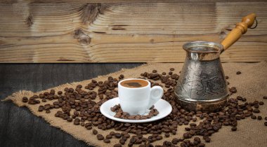 Beyaz fincanda Yunan kahvesi ve klasik kahve demliği. Ahşap zemin üzerinde fasulye olan Türk kahve fincanı. Kahve kültürü, geleneksel konsept. Metin için alanı kopyala.