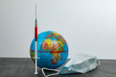 Avrupa 'da Coronavirus Covid 19 salgını ve aşı. Dünya gezegenine virüse karşı bir enjeksiyon. Şırıngayı küreye sok. Maske, şırınga ve toprak. 