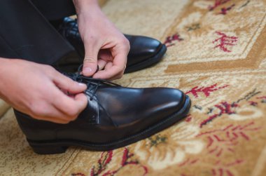 Men putting his black shoes. Hands of men getting ready in suit clipart