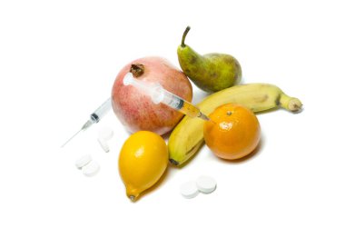 İğne ve şırınga meyve enjekte. Sağlıklı yaşam, sağlıksız hayata karşı. Masada meyve ve haplar.