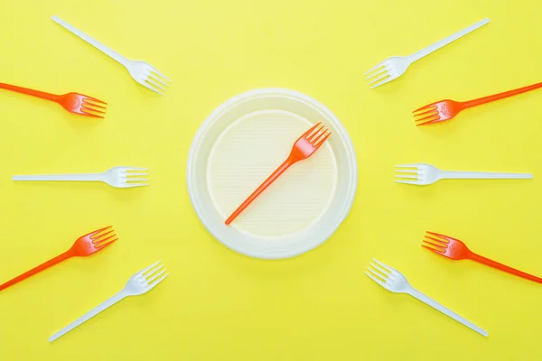 Symbol stop. Plastic forks on yellow background.