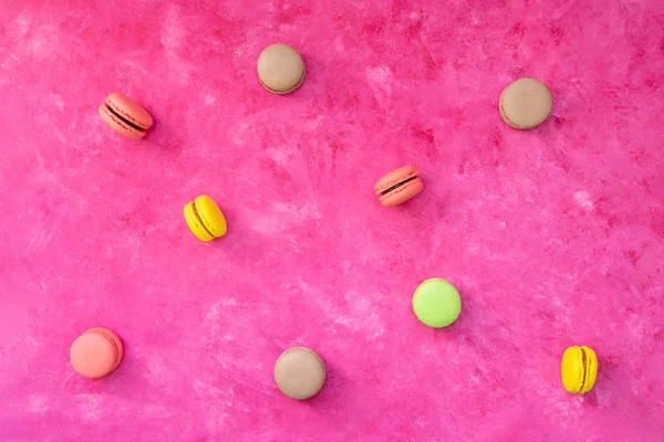 Multicolored macaroons on pink background. Top view, flat lay.