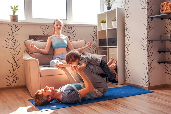 A sports family is engaged in fitness and yoga with a baby at home. Stay home in quarantine.