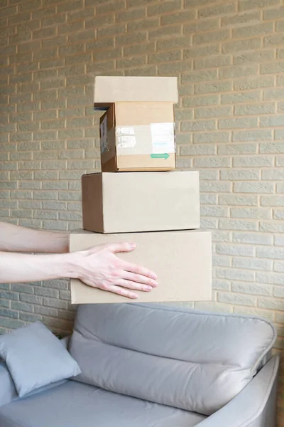 Delivery boxes stack in hands. Home interior, brick wall on background.