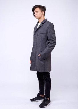 Gri kışlık montlu yakışıklı genç adam beyaz arka planda izole edilmiş..