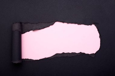 Siyah kağıtta bir delik. Yırtılmış. Pembe kağıt arka plan. Soyut arkaplan.
