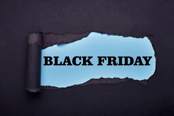 Black friday. Hole in the black paper. Torn. Blue paper background. Abstract background. — Stock Photo, Image