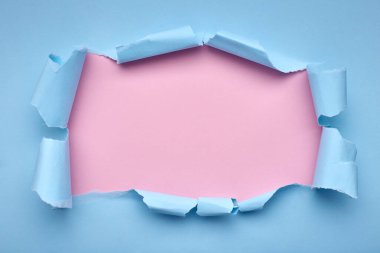 Mavi kağıtta bir delik. Yırtılmış. Pembe arka plan. Soyut arkaplan.