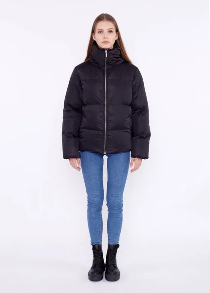 Young girl in a black down jacket and blue jeans isolated on a white background. — Stock Photo, Image