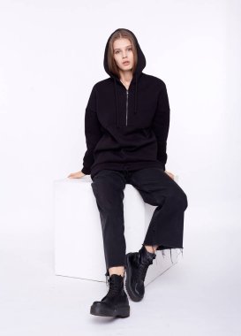 Genç kız boş ve büyük boy siyah uzun kapüşonlu giyiyor. Beyaz arkaplan