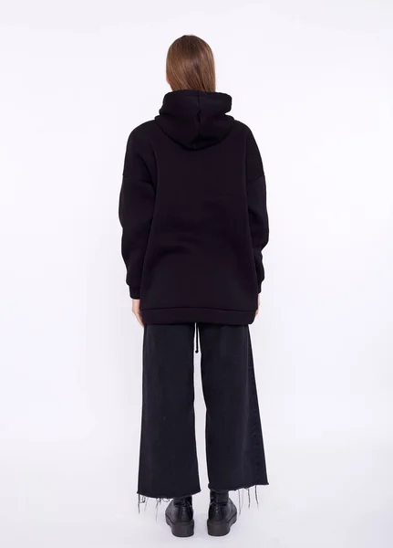 Ung flicka klädd i blank och överdimensionerad svart lång hoody. Vit bakgrund — Stockfoto