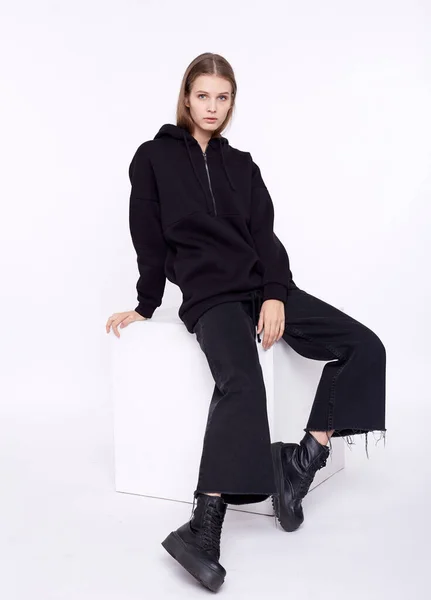 Ung flicka klädd i blank och överdimensionerad svart lång hoody. Vit bakgrund — Stockfoto