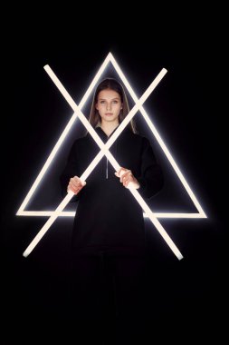 Beyaz takım elbiseli güzel kız neon lambaların ışığında poz veriyor.