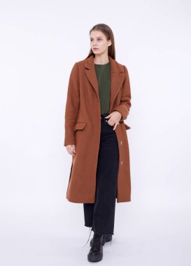 Beyaz arka planda uzun kahverengi ceketli güzel bir manken.