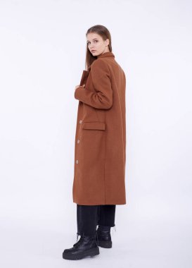 Beyaz arka planda uzun kahverengi ceketli güzel bir manken.