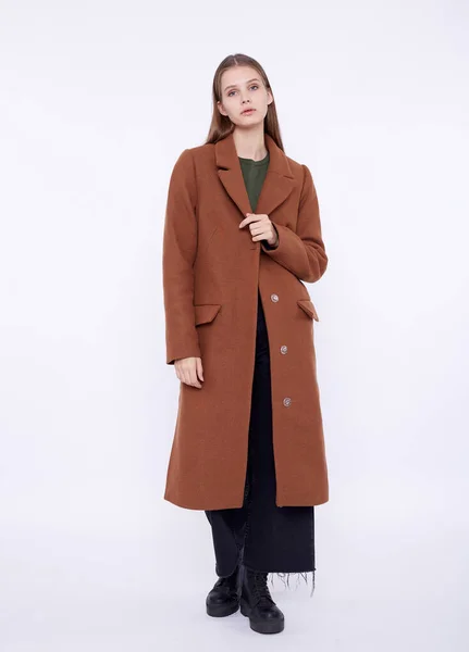 하얀 배경에 분리 된 긴 갈색 코트를 입고 있는 아름다운 패션 모델 — 스톡 사진