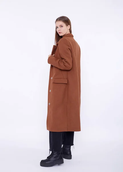 하얀 배경에 분리 된 긴 갈색 코트를 입고 있는 아름다운 패션 모델 — 스톡 사진