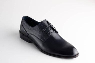 Beyaz arka planda ayakkabı bağcığı olan siyah deri ayakkabı.