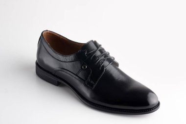 Beyaz arka planda ayakkabı bağcığı olan siyah adam deri ayakkabısı.