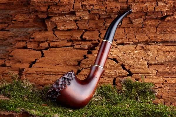 Tobacco pipe on old orange wooden background.