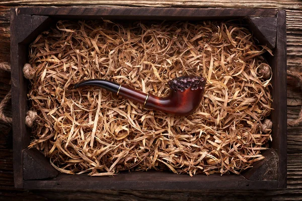 Tobacco pipe in lay in wood shavings on a wooden table .