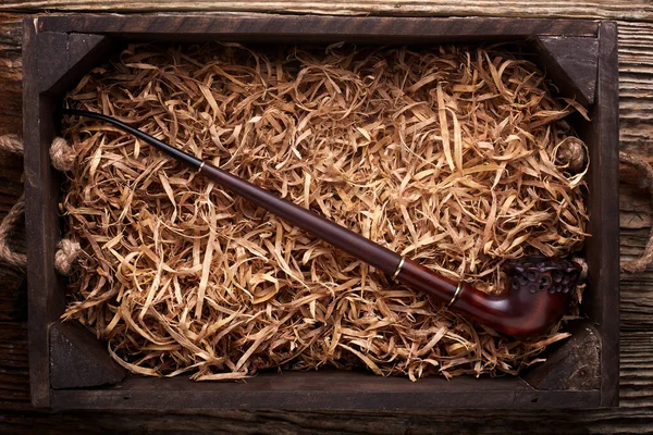 Tuyau de tabac posé en copeaux de bois sur une table en bois  . — Photo