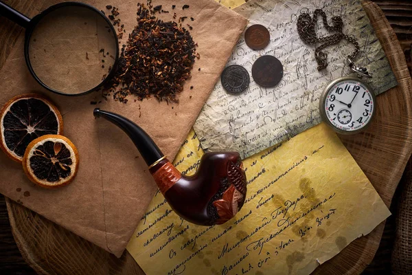 Tubería de tabaco sobre fondo de madera vieja. Letras, relojes, monedas y tabaco vintage . — Foto de Stock