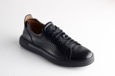 Beyaz arka planda ayakkabı bağcığı olan siyah adam deri ayakkabısı.