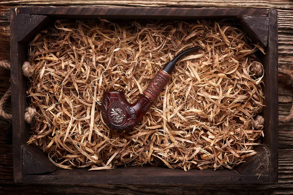 Tuyau de tabac posé en copeaux de bois sur une table en bois  . — Photo