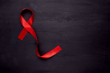 AIDS hastalığı. Siyah ahşap zemin üzerinde kırmızı kurdele, üst görünüm, kopyalama alanı.