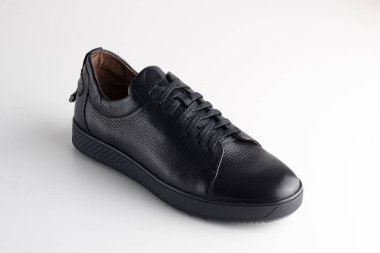 Beyaz arka planda ayakkabı bağcığı olan siyah adam deri ayakkabısı.