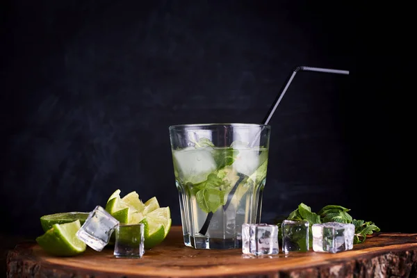 Fresh drink with lime, mint and ice on wooden table on dark background — 스톡 사진