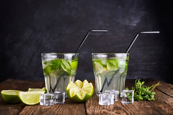 Fresh drink with lime, mint and ice on wooden table on dark background — 스톡 사진