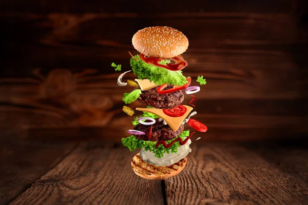 Maksimum hamburger, çift katlı çizburger ve ahşap arka planda yalıtılmış uçuş malzemeleri. Yüksek çözünürlük