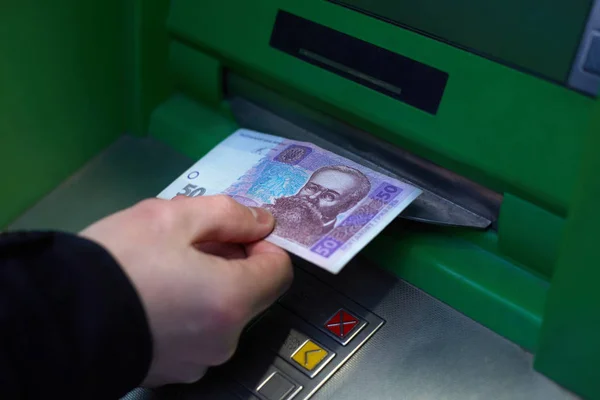 Mannelijke hand tijdens het terugtrekken van 50 Oekraïense hryvnia uit een Atm. De afschrijving van de nationale munteenheid, de Duitse mark. — Stockfoto