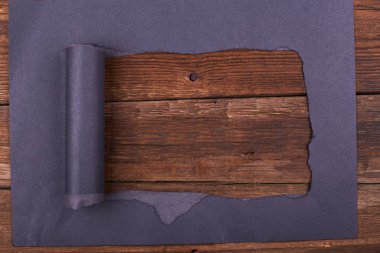 Siyah kağıtta büyük bir delik var. Yırtılmış. Ahşap arka plan. Soyut arkaplan.