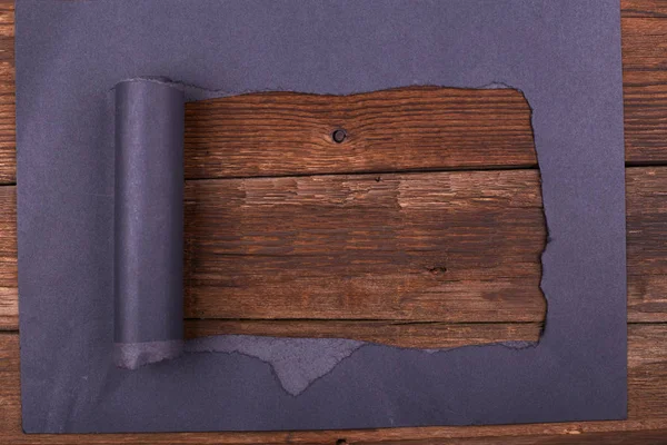 Siyah kağıtta büyük bir delik var. Yırtılmış. Ahşap arka plan. Soyut arkaplan.