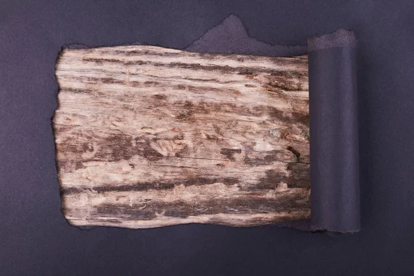 Siyah kağıtta büyük bir delik var. Yırtılmış. Ahşap arka plan. Soyut arkaplan.